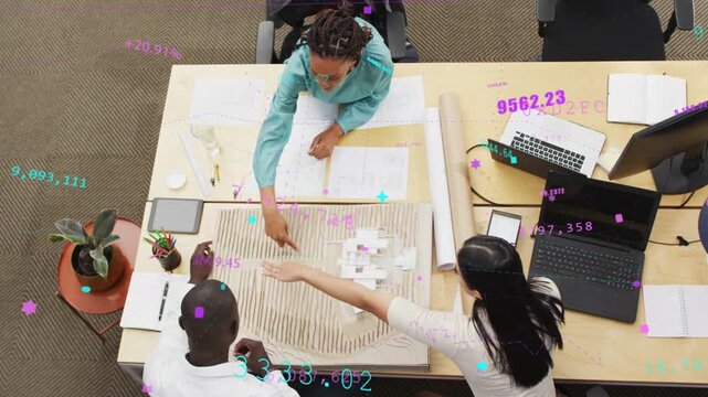 Lead woman leaning and pointing, guiding right woman in placing white blocks in design model