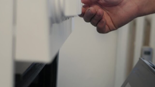 A Man in the Kitchen Opens the Stove Door and Rotates the Gas Button Increasing or Decreasing the Fire and Inside Temperature.