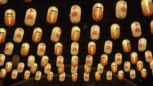 Many Japanese lanterns hung with lights on. Japanese means cheers and happy new year.
