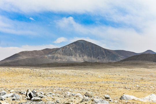 Barren high-altitude Himalayan landscape with rugged mountain, rocky terrain and sparse vegetation under blue sky, dramatic North Sikkim scenery, India.