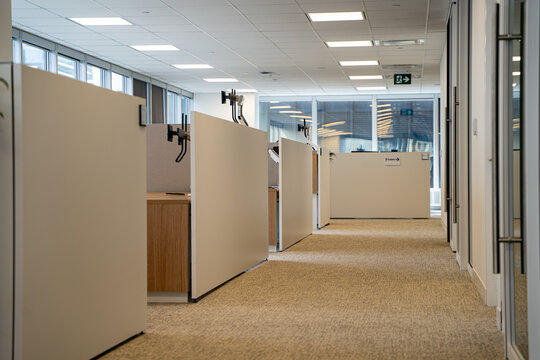 Modern office corridor with cubicles and empty workspace interior.