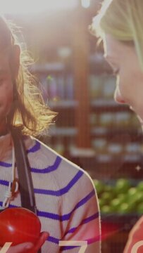 Vertical video: Seller holding tomato in market making charts showing stats over tomato for buyer