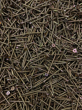 Zinc wood screws. Golden galvanized metal fasteners for woodworking. Texture of many steel wood-screws with sharp points and threads