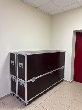 Large professional flight cases on wheels standing in hallway. Hard case on wheels for transport or shipment of high-value equipment, musical instruments, and lighting gear.
