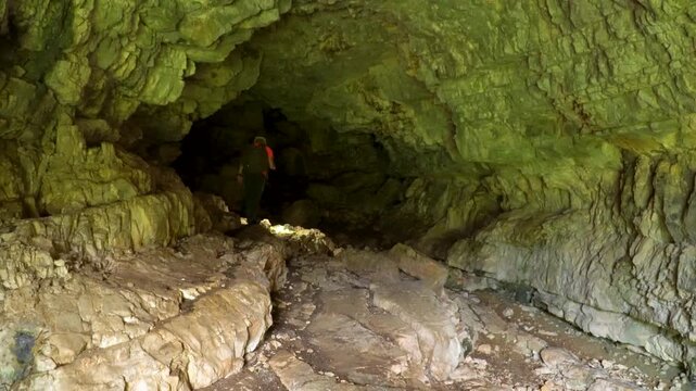 Hiker exploring a dark cave with a torch.