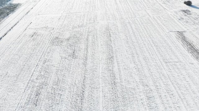 Aerial winter farmland with crossing tractor tracks