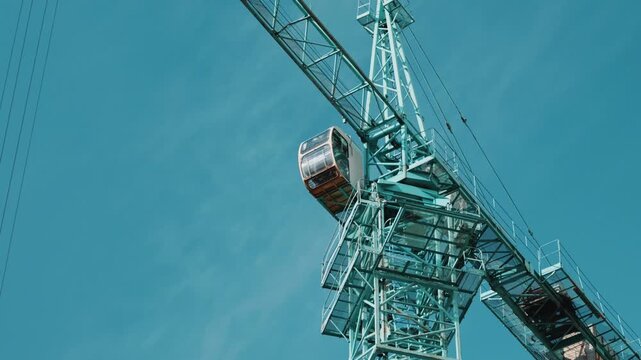 Tower crane jib rotating against blue sky