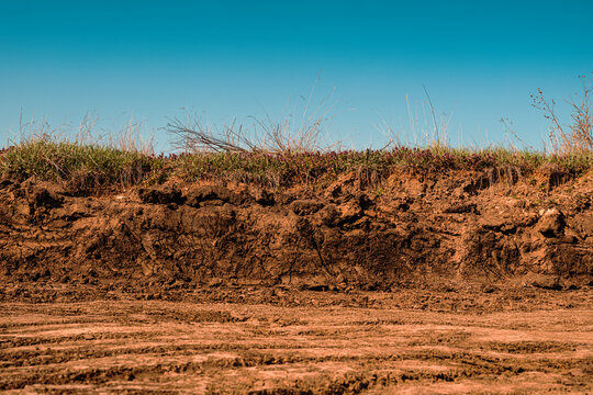 Excavated dirt road construction site under clear blue sky, earthworks and infrastructure development concept