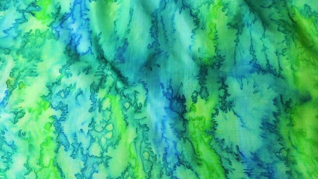 Abstract waves of natural silk fabric fluttering in the wind. Flowing background with organic green and blue watercolor textures. Soft ripples of turquoise and lime textile creating a dynamic motion.