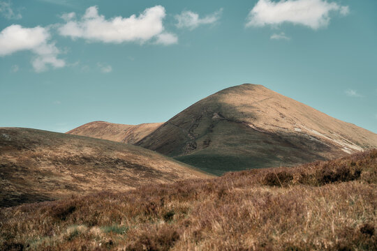 Rolling Hills and Mountain Peak Under Blue Sky