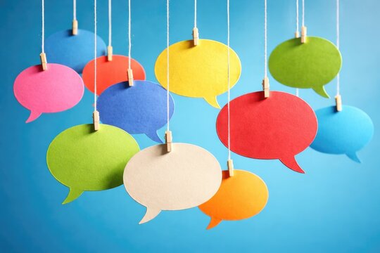 Multicolored dialogue bubbles dangling on a thread against blue background