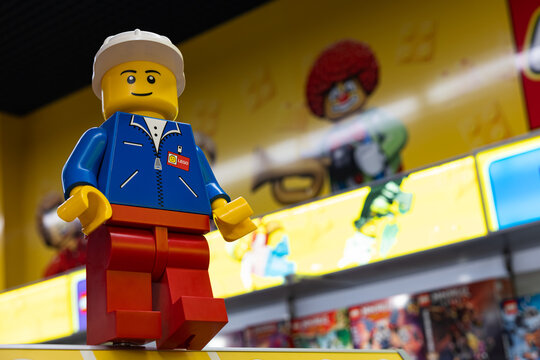 LEGO worker minifigure on yellow display shelf in store