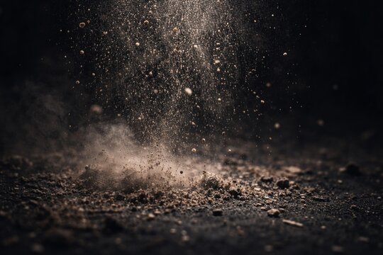 Close up view of fine dust and scattered debris descending on a dark surface