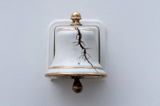 A cracked white ceramic bell on the wall. Space for text.