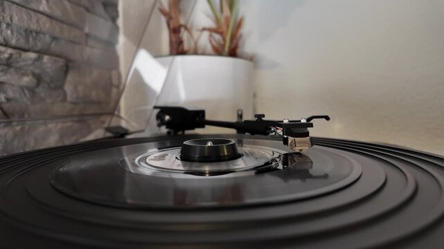 Close up of vinyl record spinning on turntable with needle in cozy home interior