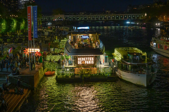 PARIS, FRANCE &mdash; APRIL 11 2024: illuminated Vedettes de Paris tour boats and Francette restaurant vessel moored at the Port de la Conf&eacute;rence at night.