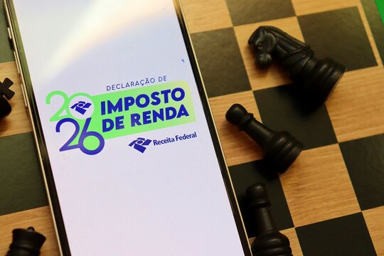 Salvador, Brazil - April 19, 2026: Receita Federal Imposto de Renda 2026 logo on a smartphone screen on top of a chessboard. Brazilian income tax  (Declara&ccedil;&atilde;o do Imposto de Renda) strategy. 