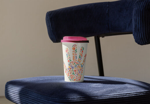 Eco-friendly Takeaway Cup With Color Lid Sits on a Chair. PSD Template Mockup.