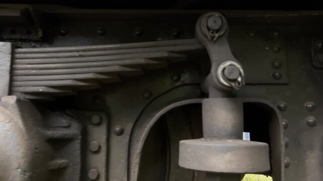 Cinematic slide shot moving left to right of a vintage train bogie and metal leaf spring suspension system, industrial railway mechanical detail