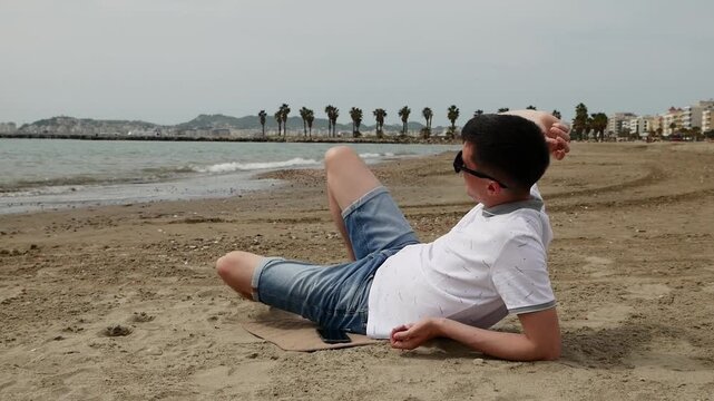 Man enjoying the beach by tossing stones into the sea, outdoor relaxation and fun.