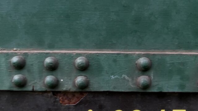 Close-up slide shot moving left to right over vintage train carriage metal riveting, industrial texture detail