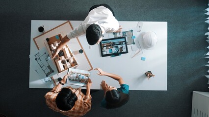 Naklejka premium Top down view of civil architect looking at project plan while present to investor at meeting table. Aerial view of skilled designer explain about construction to business people listen. Alimentation.