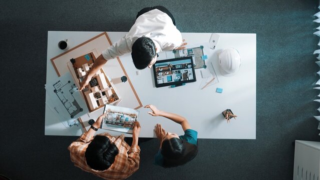 Top down view of civil architect looking at project plan while present to investor at meeting table. Aerial view of skilled designer explain about construction to business people listen. Alimentation.