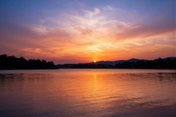 Fototapeta premium Sun setting over calm lake with colorful sky reflections