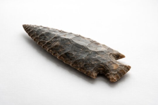 Ancient flint arrowhead showcased on a clean white background