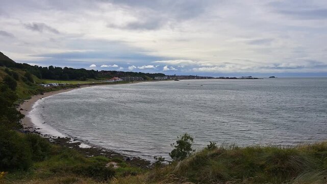 K&uuml;stenlinie mit Strand und Bucht unter einem bew&ouml;lkten Himmel, Geb&auml;ude im Hintergrund, North Berwick, East Lothian, Schottland, Vereinigtes K&ouml;nigreich, Gro&szlig;britannien 