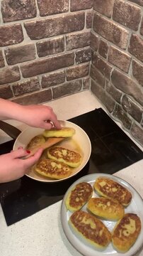 Perfect golden-brown crust! Close-up of flipping potato zrazy (stuffed potato pancakes) in a frying pan with oil. Cozy home cooking video.