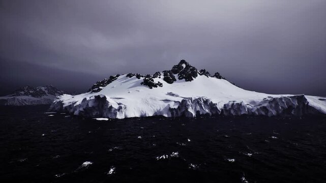 Moody twilight volcanic island with snow, jagged black peaks rising from dark sea, low diffuse light under brooding storm clouds, icy shoreline and scattered