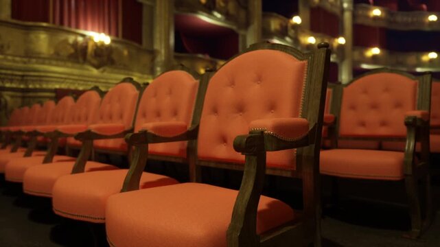 Empty house ready for opening night, plush red seats and gilded balconies bask in low light, hush of backstage preparations implied, glamorous vintage ambience