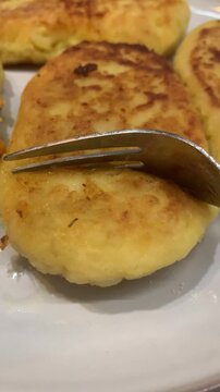 A silver fork breaking into a soft, golden-brown fried patty on a plate. The shot reveals the tender texture and delicious vegetable stuffing. Ideal for food reviews, restaurant promos, or cooking blo