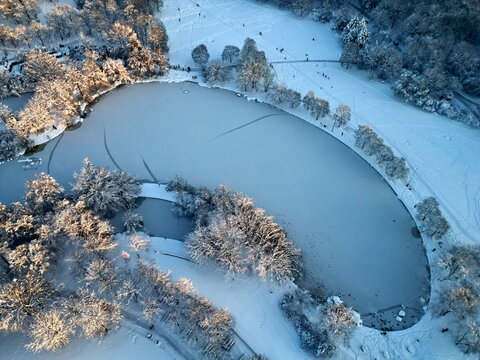 Aerial view of frozen Mollsee lake with ice tracks in Westpark Munich.