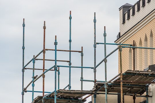 Scaffolding structure in an ongoing urban construction, with building materials and a multi-story building under construction Overcast daytime lighting