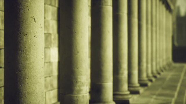 Closeup stone colonnade Alexandria showing textured pillars receding into soft shadows, warm toning, ancient masonry and quiet atmosphere.