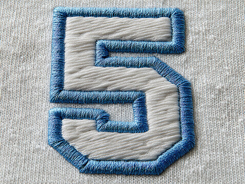 Close-up of a white fabric item with a stitched number 5 in sky blue and embroidered letter S The embroidery features dense, textured blue stitches - AI-Generated