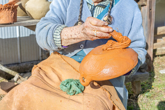 Cauquenes, Chile - March 26, 2026: An artisan proceeds to apply the "colo", a paste that gives the characteristic reddish-brown color to clay pieces such as bowls, cups, jugs, among others.