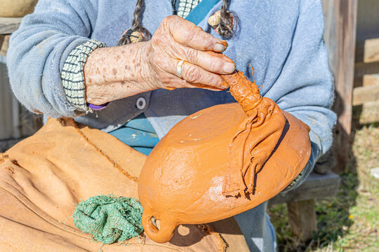 Cauquenes, Chile - March 26, 2026: An artisan proceeds to apply the "colo", a paste that gives the characteristic reddish-brown color to clay pieces such as plates, cups, jugs, among others.