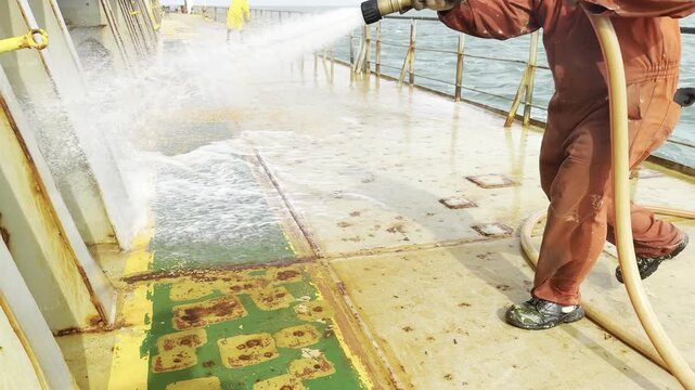 ship crew remove the cargo residues from deck by the water from fire system. seafarer job and life.