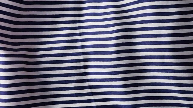 Blue and white striped silk fabric waving in the wind. Abstract background with smooth nautical pattern waves. Natural flowing textile motion for creative design projects. 