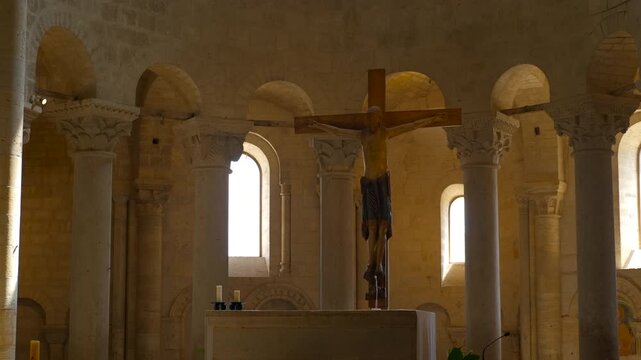 Sunlight moving across columns in romanesque abbey. Moving sunlight illuminating the altar, crucifix, and stone columns inside a historic romanesque abbey, creating a serene and spiritual atmosphere