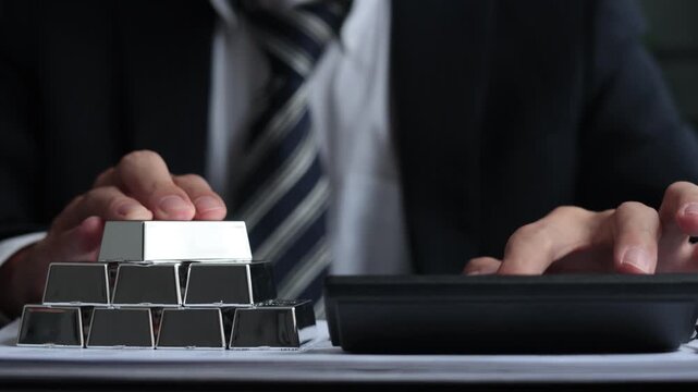 Silver Bullion Investment and Financial Analysis. Businessman Calculating Investment Returns with Silver Bars on The Table.