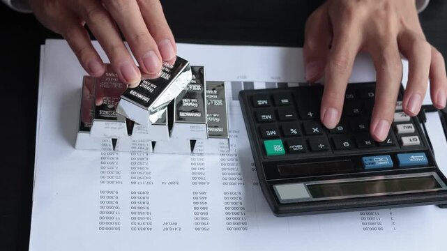 Silver Bullion Investment and Financial Analysis. Businessman Calculating Investment Returns with Silver Bars and Financial Documents.