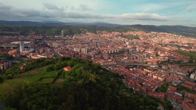 Aerial drone view of Bilbao at sunset with skyline, neighborhoods and warm golden light. Scenic urban landscape in Basque Country, northern Spain. High quality 4k footage