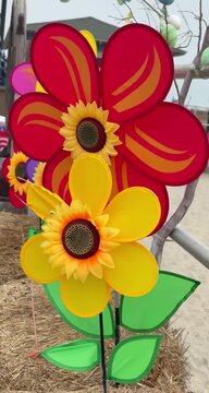 Vertical view of colorful flower shaped pinwheels spinning quickly in a strong wind