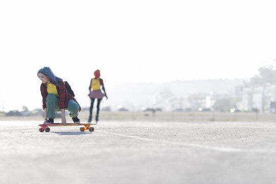 Young woman crouching on skateboard preparing to ride