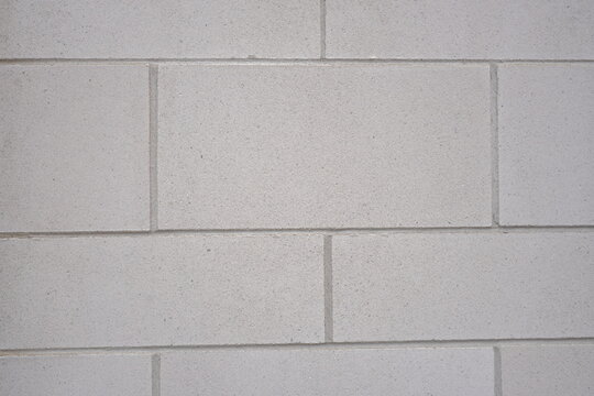 Flat lay perspective of a light grey concrete block wall with clean mortar lines, showing a fine sandy texture.