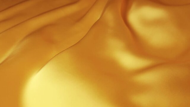 Abstract golden natural silk fabric waving in the wind. Smooth elegant flowing waves creating a luxury background. Seamless motion of yellow and orange soft textile.
